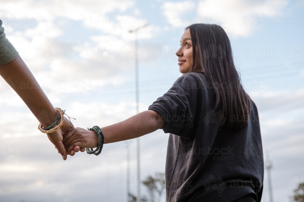 Two Aboriginal girls wearing traditional woven bracelets, holding hands - Australian Stock Image