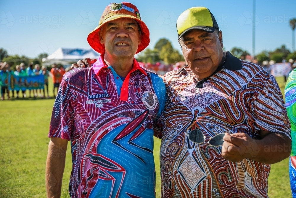 Two aboriginal males in hats standing with arm around each other - Australian Stock Image