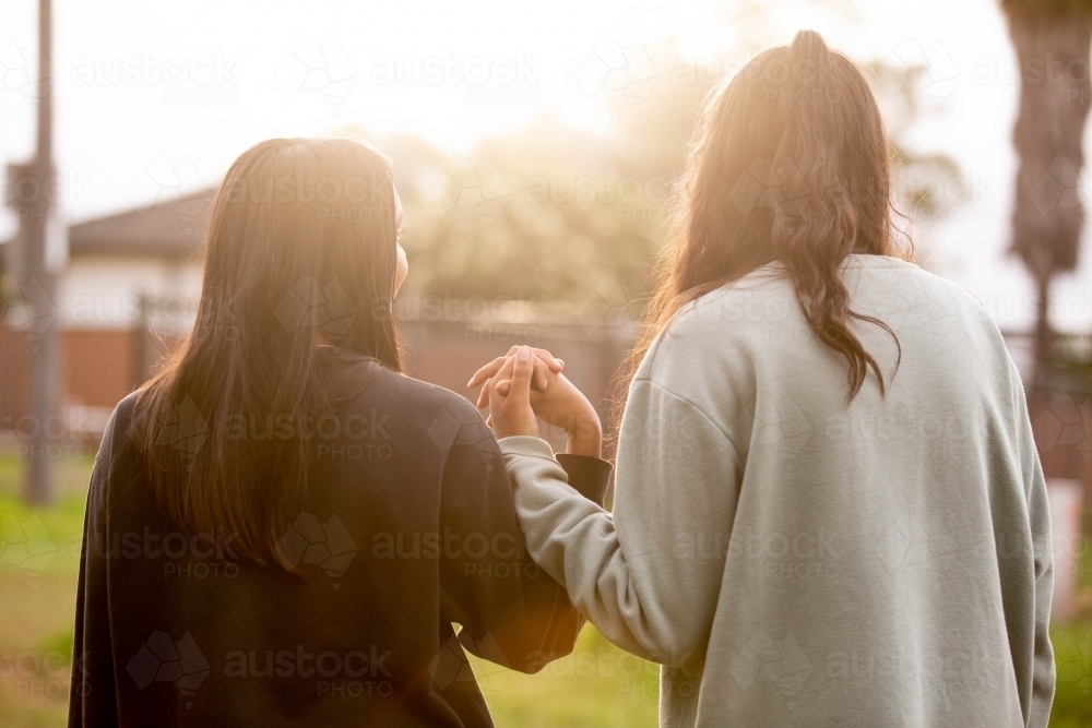 Two Aboriginal young women walking together holding hands - Australian Stock Image