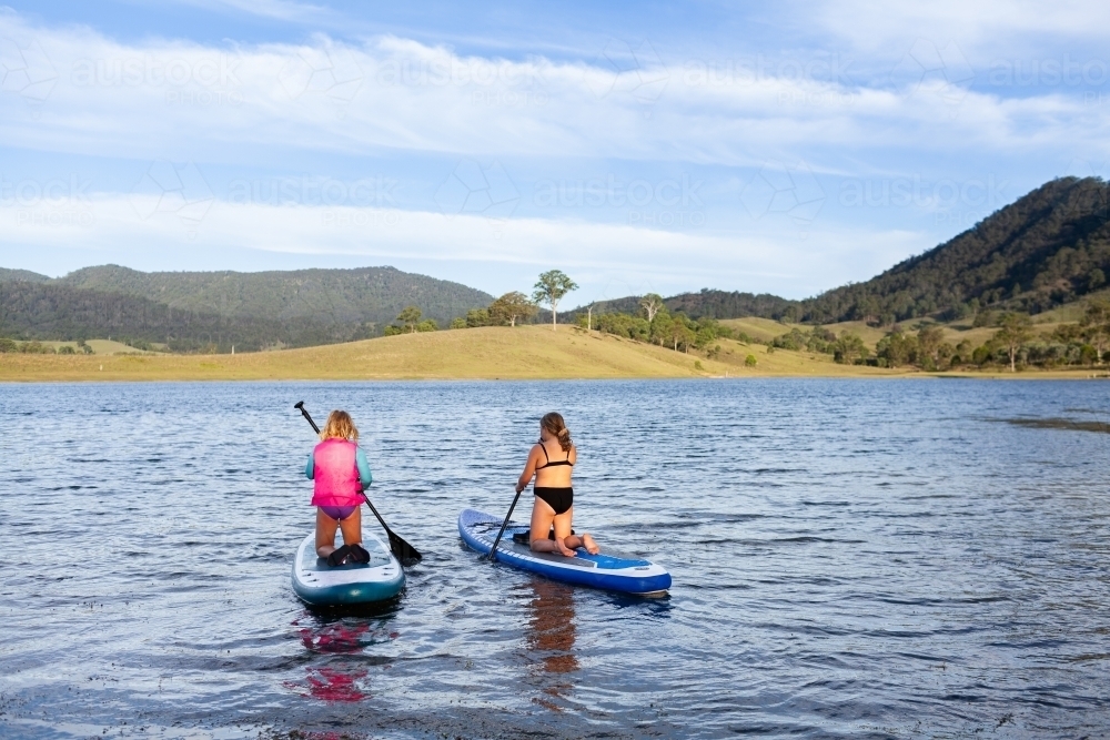 Two Aussie kids out on paddle board on Lake St Clair in summer  - Australian Stock Image