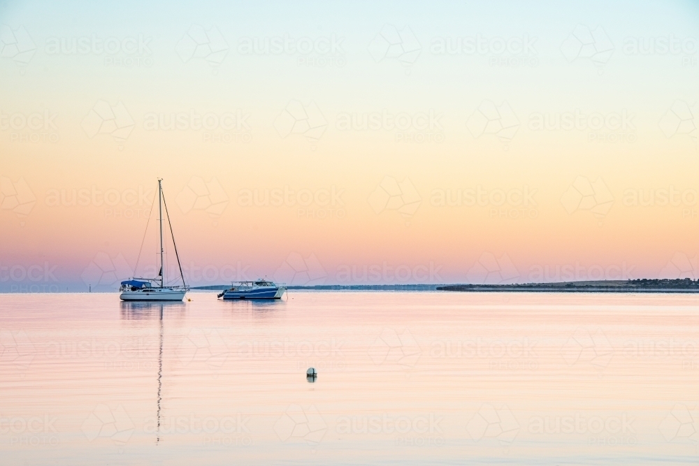 Two boat on a clear still morning water at dawn - Australian Stock Image