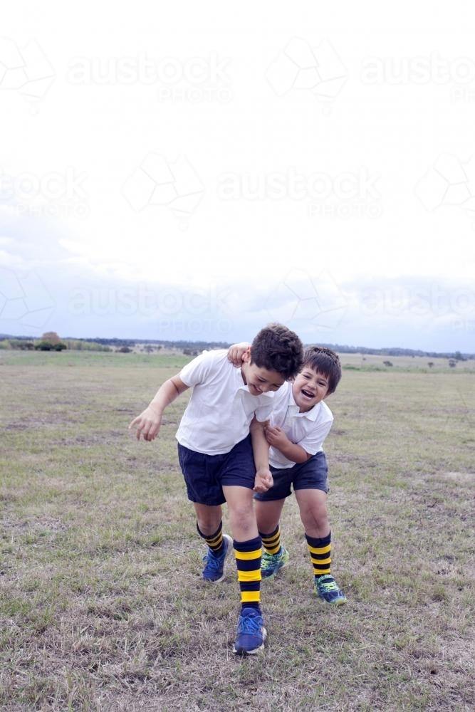 Two boys chasing after each other wearing football socks - Australian Stock Image