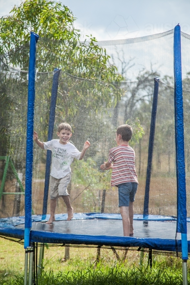 Image of Two boys jumping on the trampoline in the rain Austockphoto
