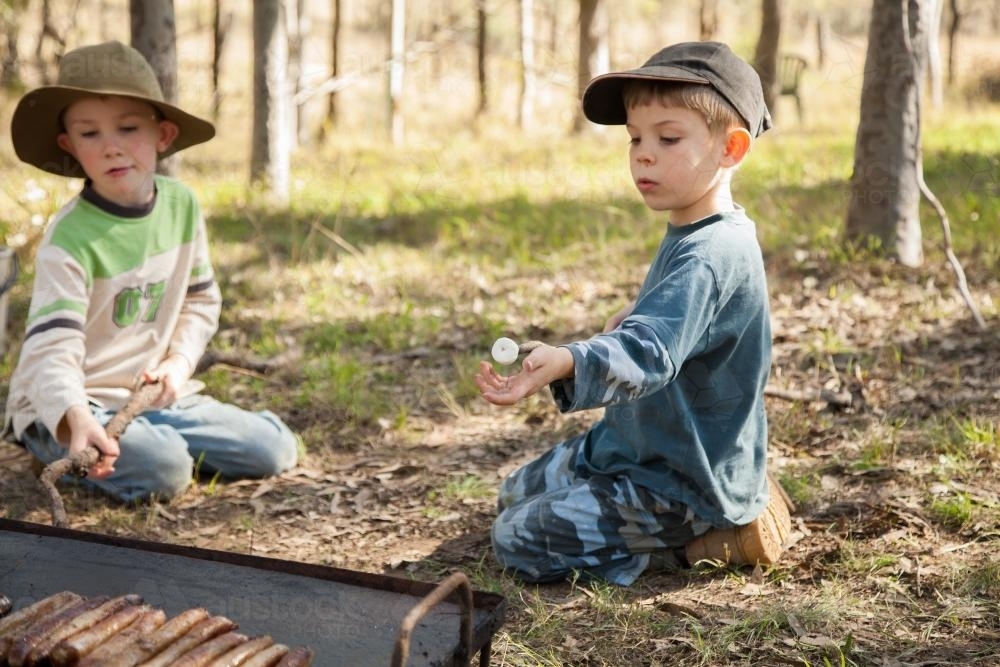Two brothers cooking marshmallows on the campfire - Australian Stock Image