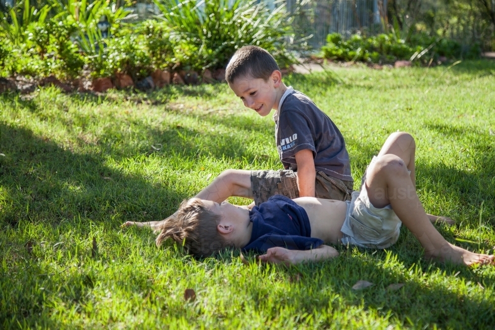 Two brothers tackling on the grass outside - Australian Stock Image