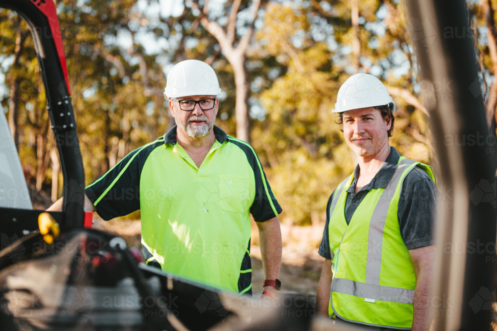 Two builders standing next to ute on worksite wearing hardhats and high vis - Australian Stock Image