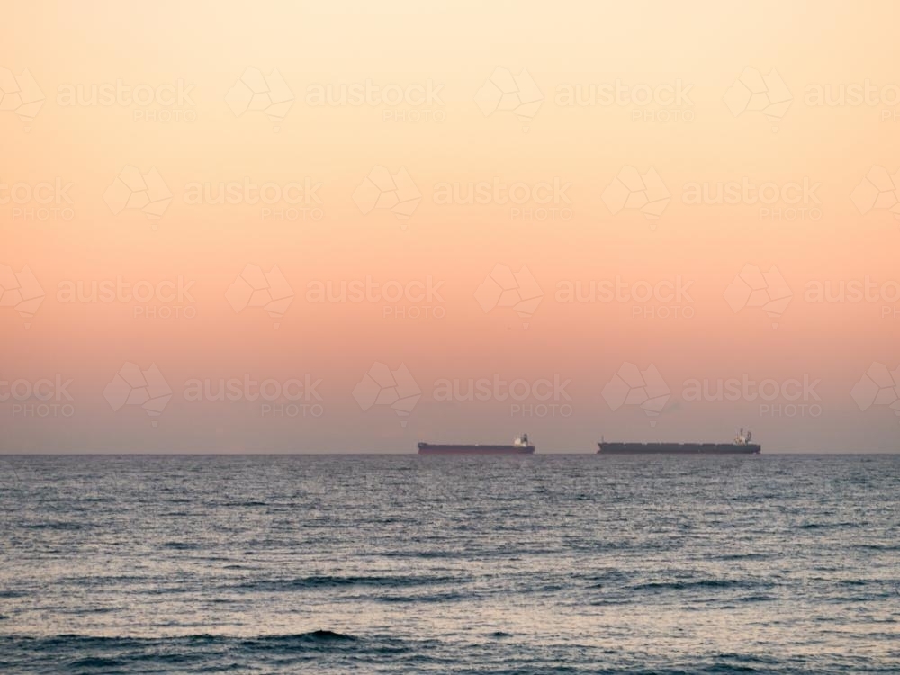 Two bulk carriers (ships) on the horizon at dusk - Australian Stock Image