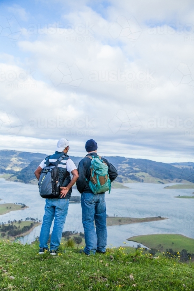 Two bushwalkers standing on a hill overlooking Lake St Clair - Australian Stock Image
