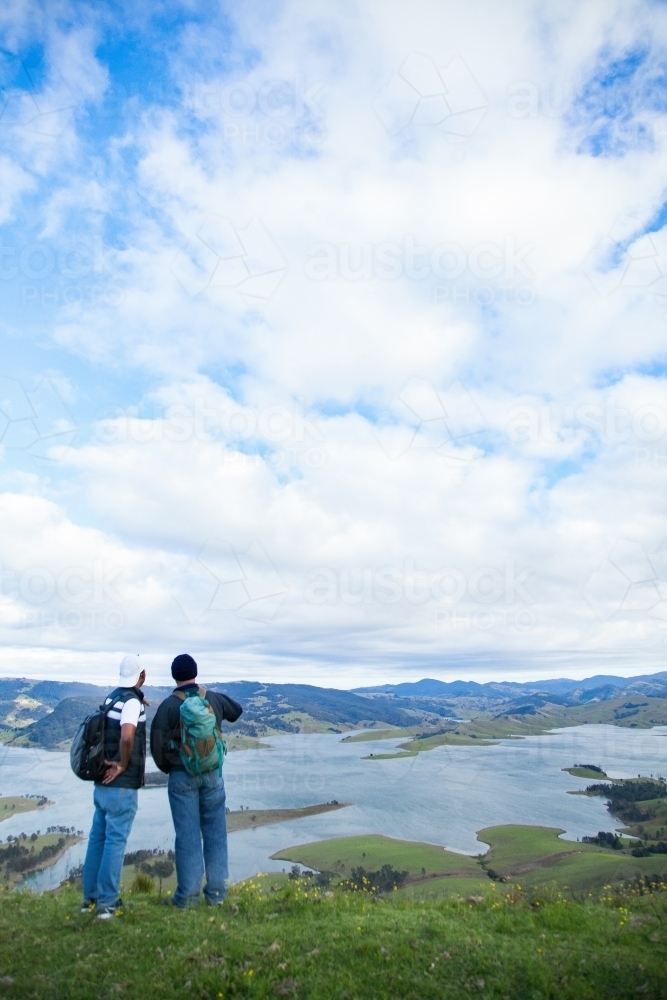 Two bushwalkers standing on a hill overlooking Lake St Clair - Australian Stock Image