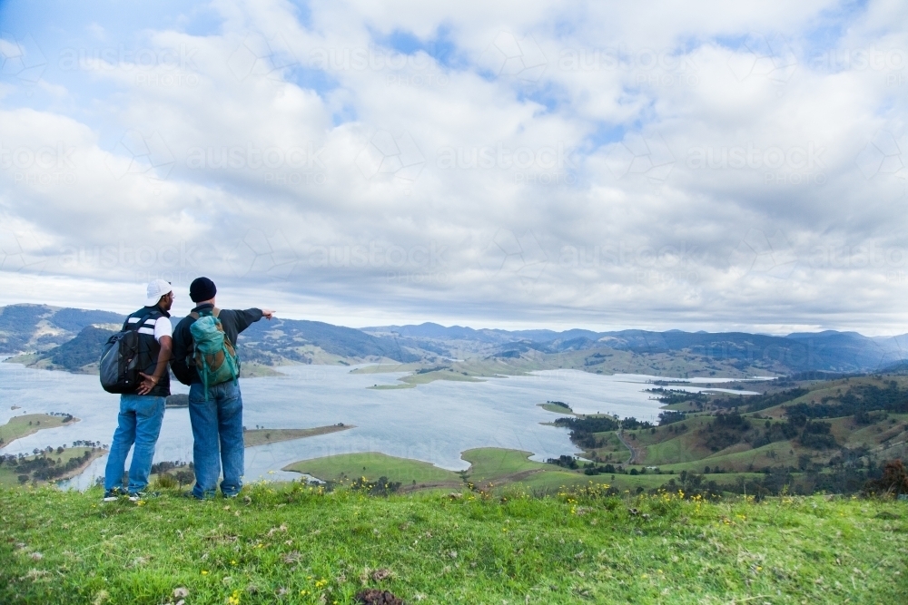 Two bushwalkers standing on a hill overlooking Lake St Clair - Australian Stock Image