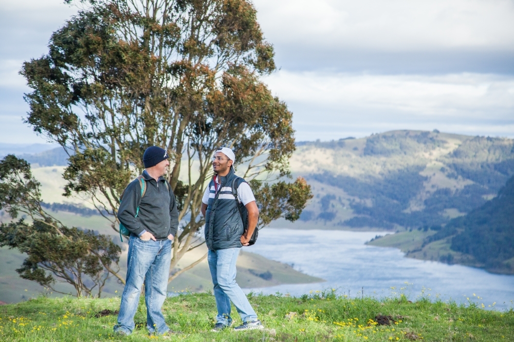 Two bushwalkers standing on a hill overlooking Lake St Clair - Australian Stock Image