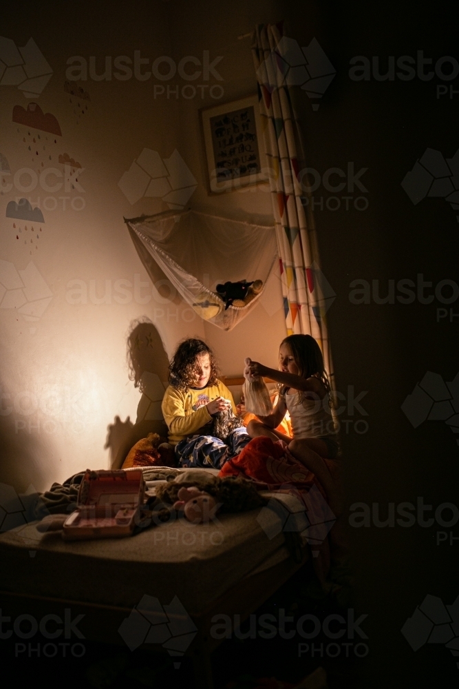 Two children in a bedroom at night playing by the lamplight - Australian Stock Image