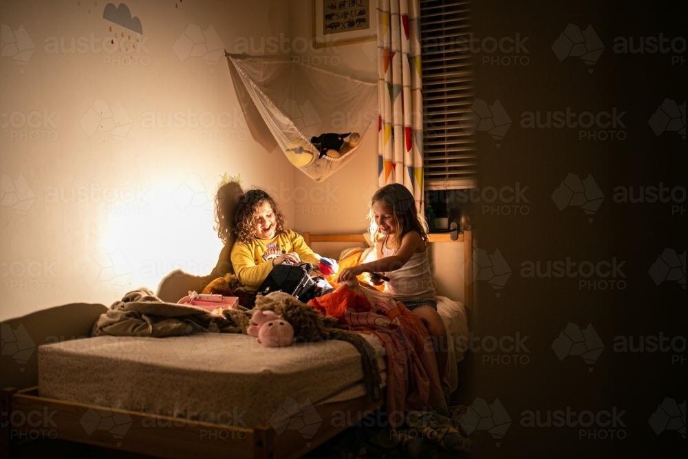 Two children in a bedroom at night playing by the lamplight - Australian Stock Image