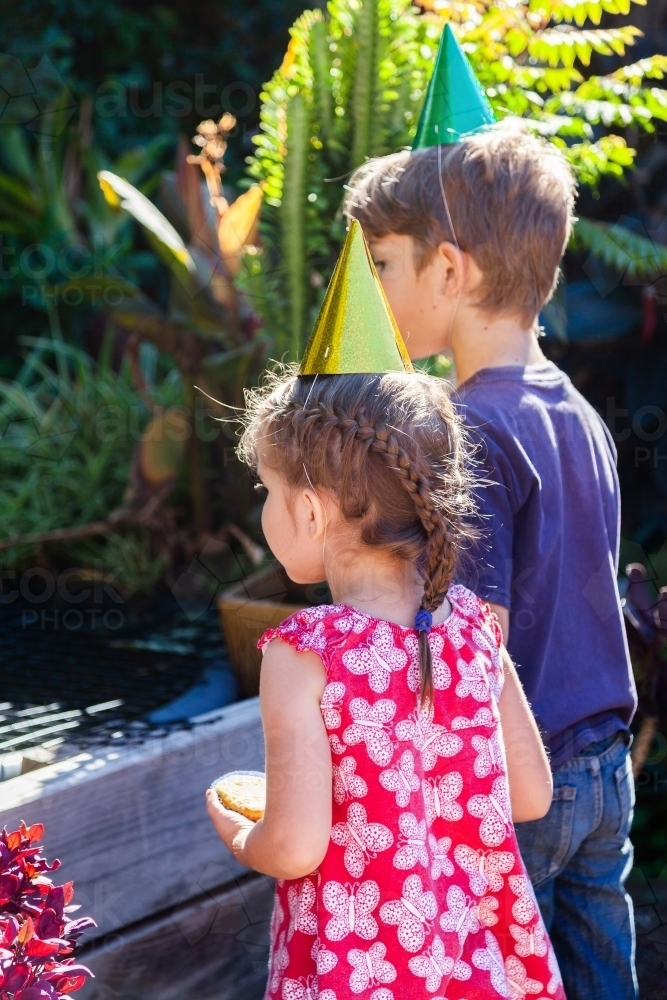 Two children looking at fish pond in garden - Australian Stock Image