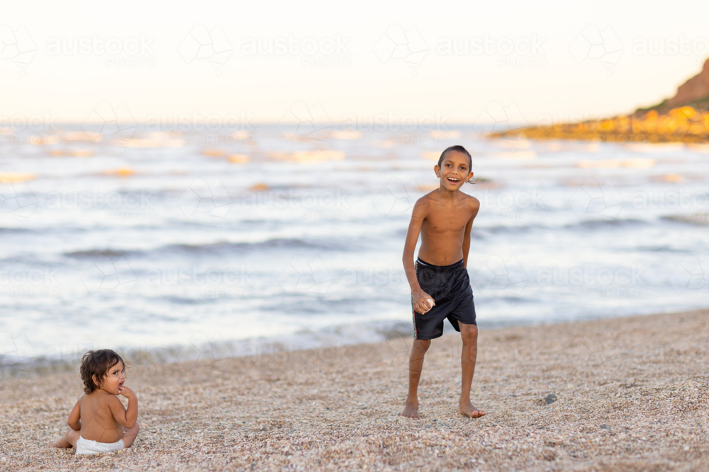 two children on a beach with course sand and choppy sea - Australian Stock Image
