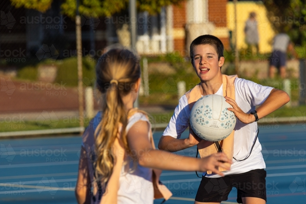two children on an outdoor netball court passing the ball - Australian Stock Image