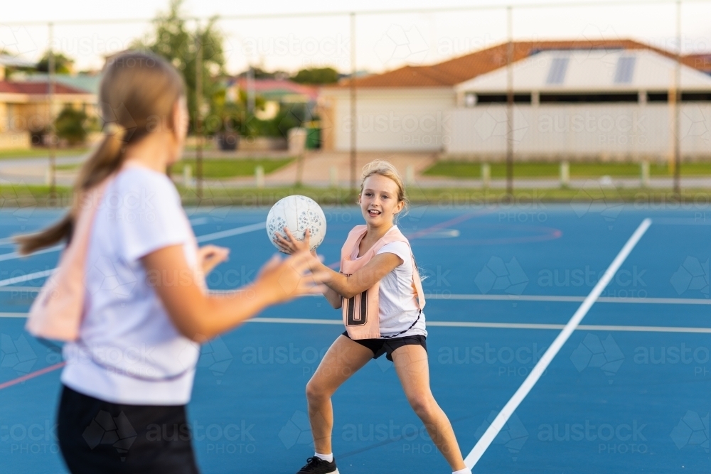 Image of two children playing netball on outside netball court ...