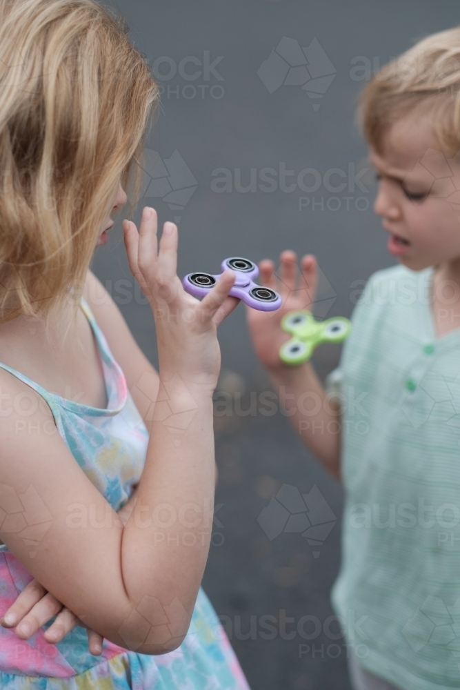 Two children playing with fidget spinner toys - Australian Stock Image