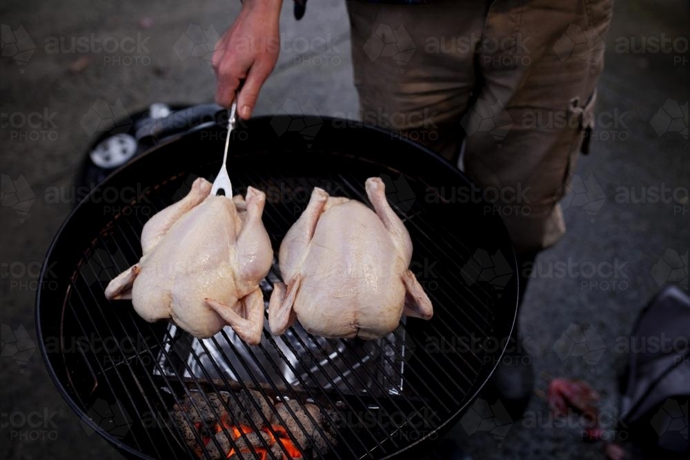 Two chooks cooking on a small round bbq - Australian Stock Image