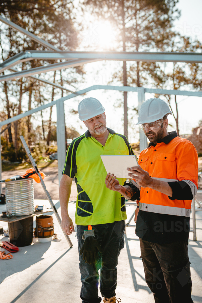 Image of Two construction site managers looking at digital blueprints ...