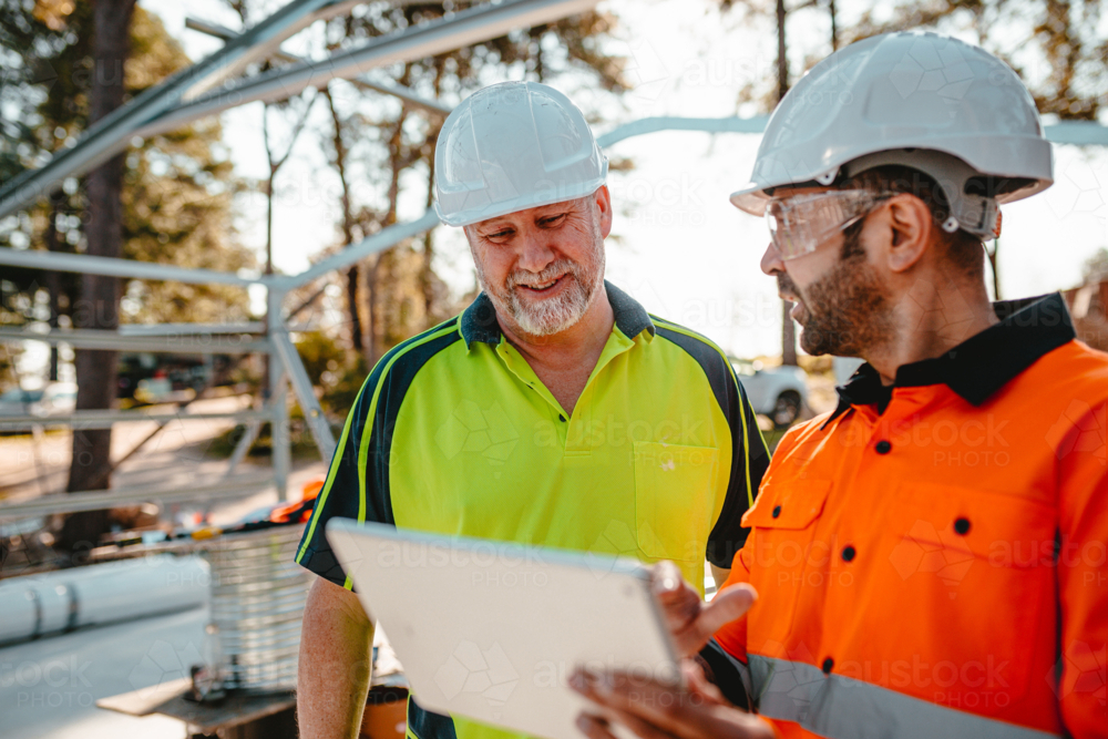 Two construction site managers looking at the digital blueprints. - Australian Stock Image