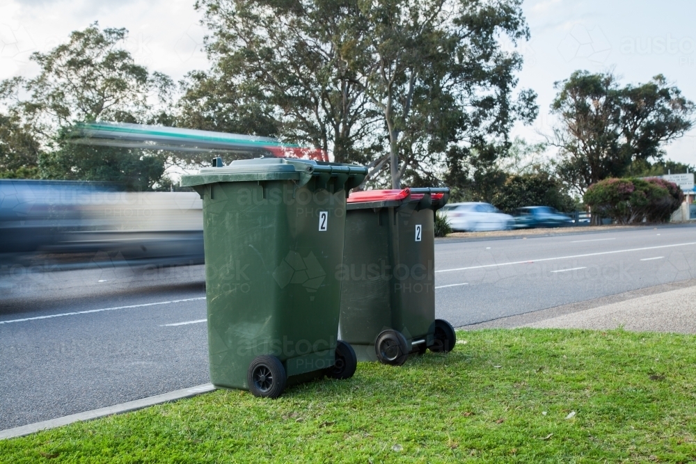 Image of Two council bins awaiting collection beside a busy road