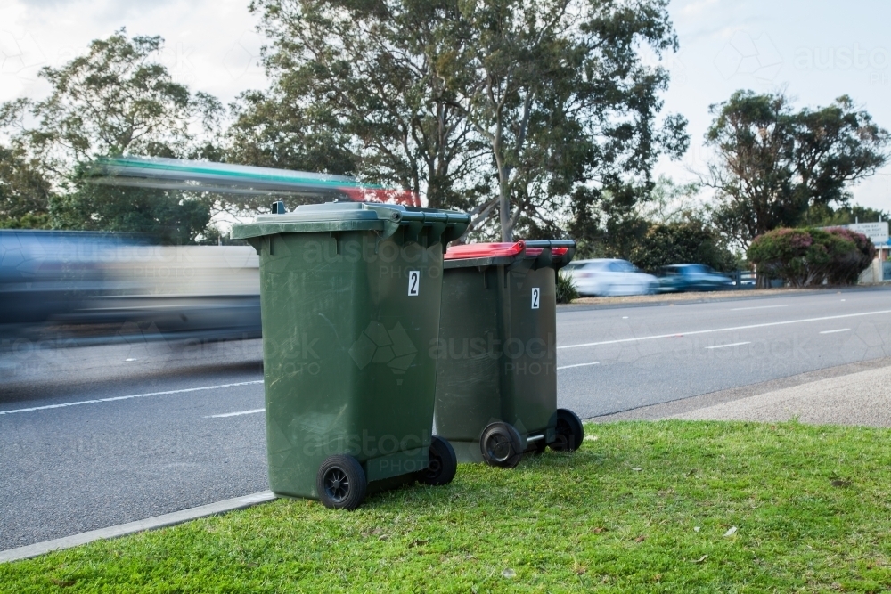 Two council bins awaiting collection beside a busy road - Australian Stock Image