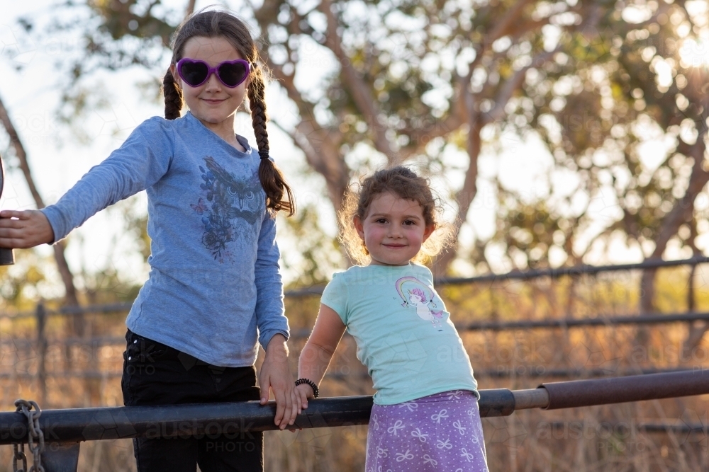 Two country kids on playing on a gate - Australian Stock Image