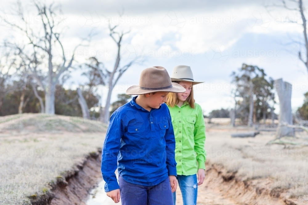 Two country kids walking along a creek - Australian Stock Image