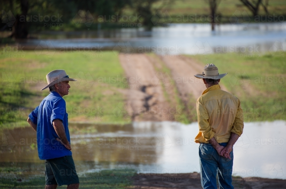 Two farmers talking near a flooded creek - Australian Stock Image