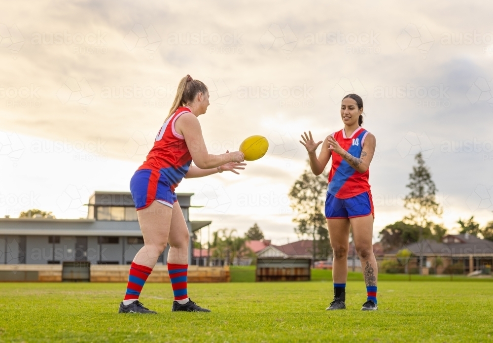 Two female football players passing the ball at training - Australian Stock Image