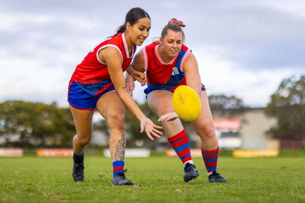 two female footballers scrambling to tap the ball away - Australian Stock Image