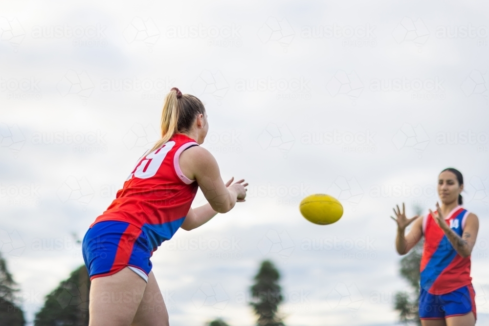 Image of two female footy players practising handball drills Austockphoto