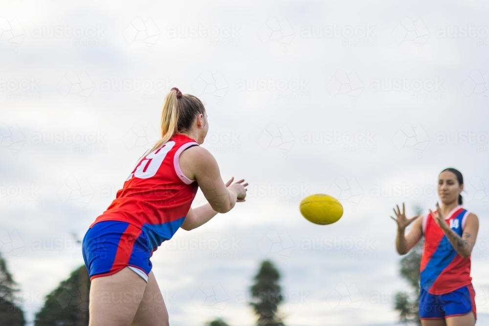 two female footy players practising handball drills - Australian Stock Image