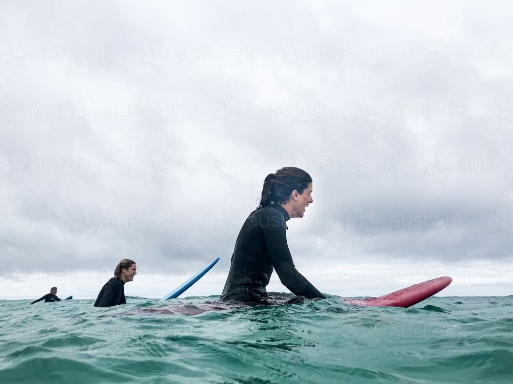 Two female surfers waiting for next wave on surfboards in ocean - Australian Stock Image