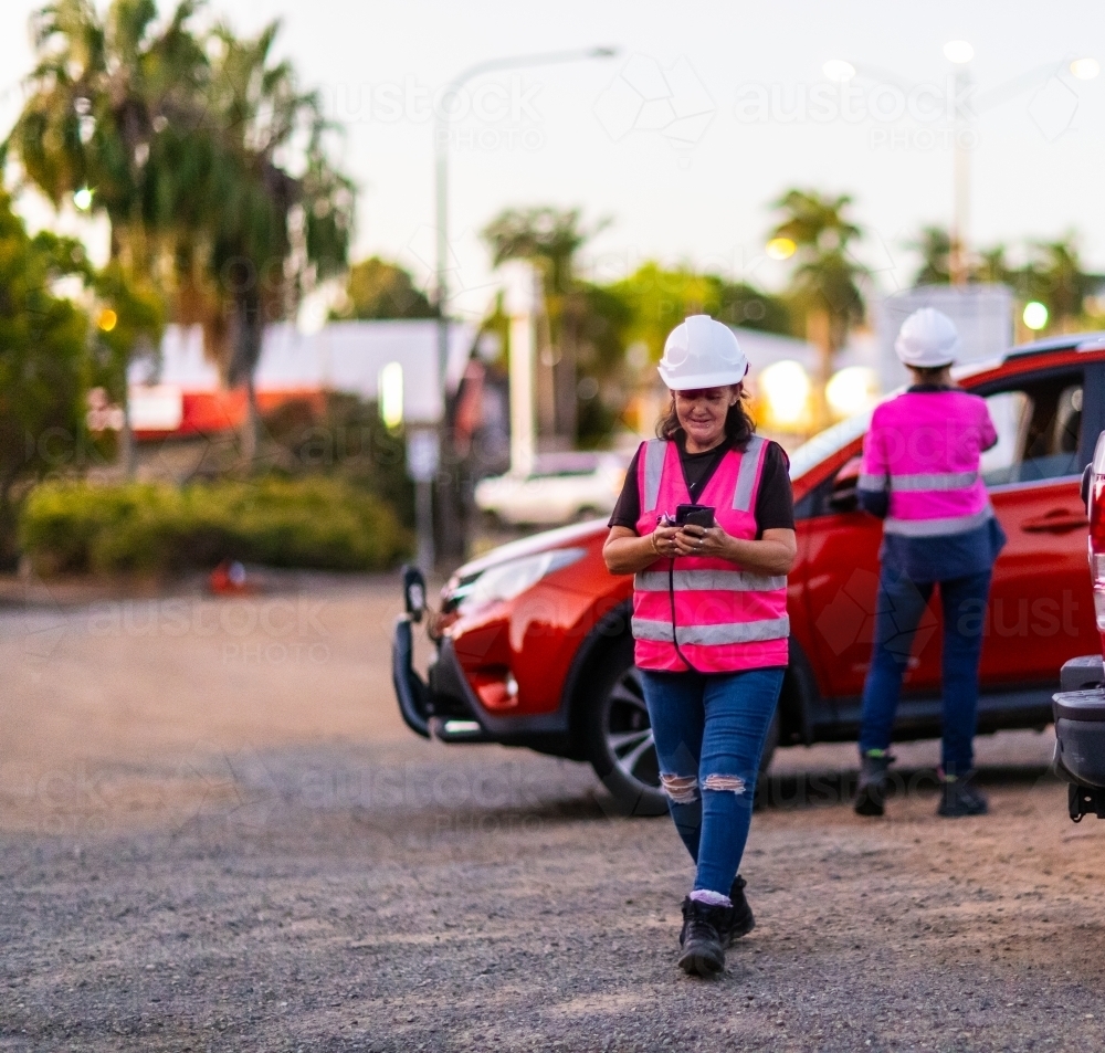 two female workers arriving at worksite wearing hi-vis and hard hats - Australian Stock Image