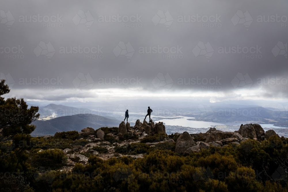 Two figures on a mountain top in the clouds - Australian Stock Image
