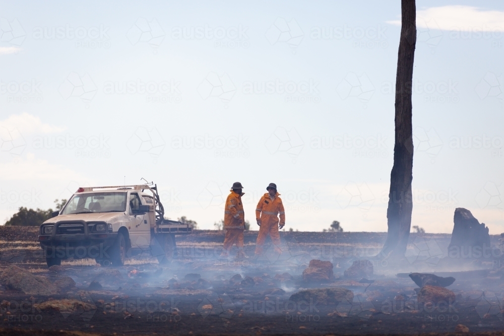 two fire service volunteers with vehicle in burnt out landscape with smoke - Australian Stock Image