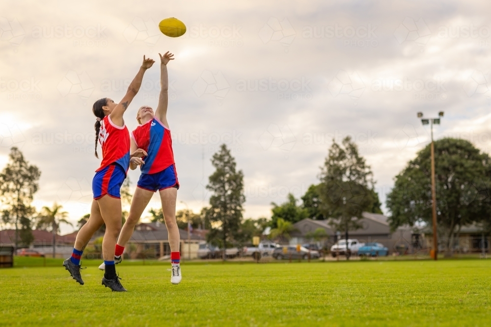 two footy players stretching up to tap the ball away - Australian Stock Image