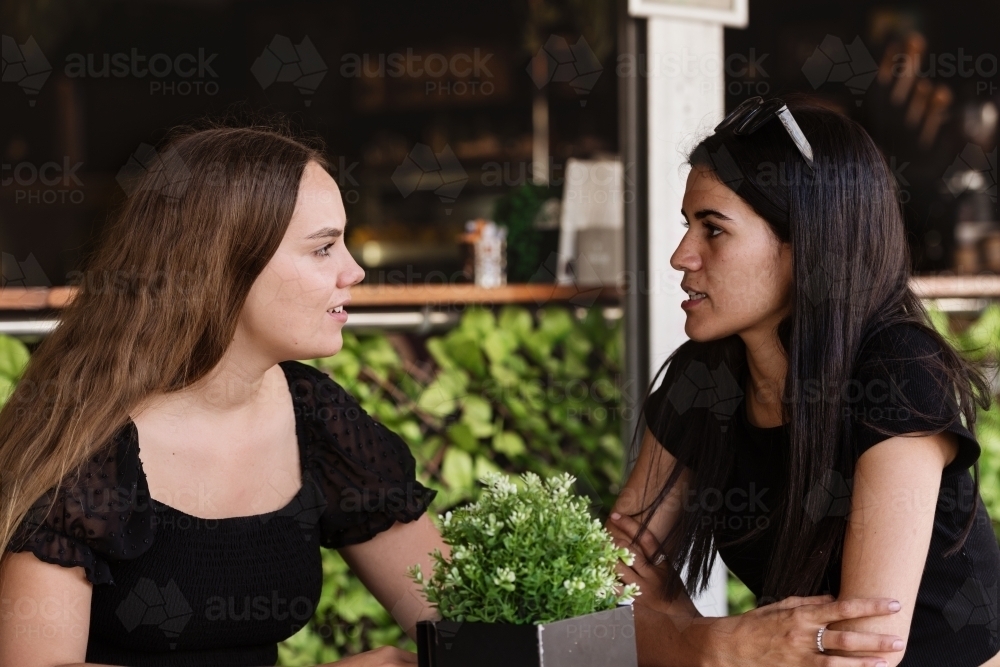 Image of two friends chatting in a cafe - Austockphoto