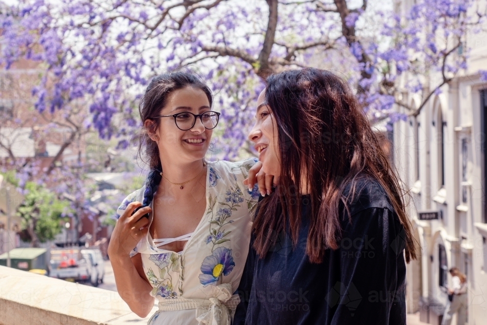 two friends chatting under jacaranda trees - Australian Stock Image