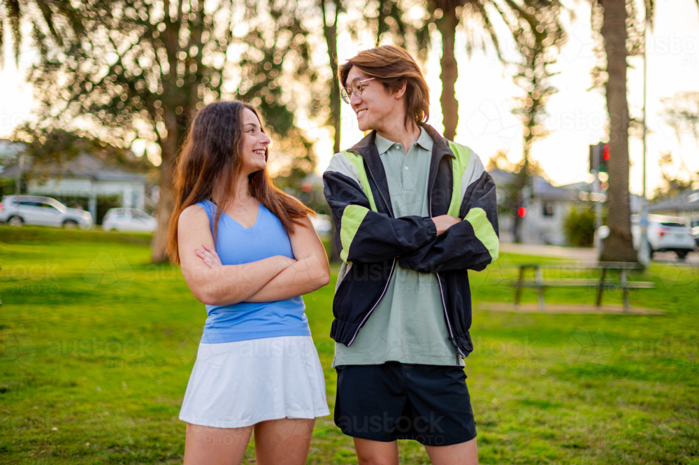 Two friends enjoying each other's company at a park during sunset. - Australian Stock Image