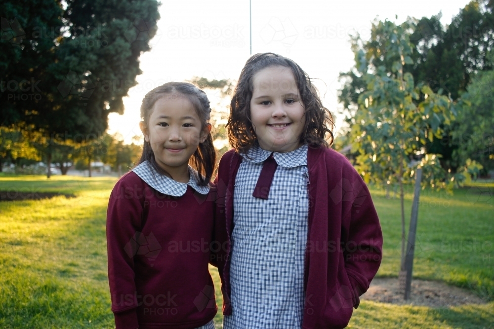Image of Two friends in school uniform standing together outside