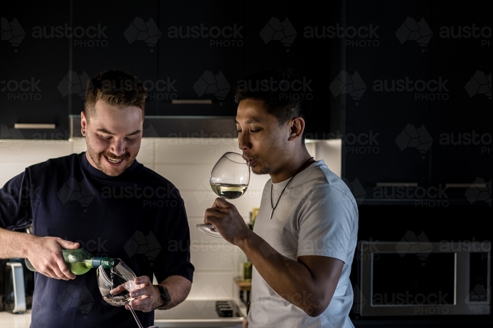 Two gay men enjoying a glass of wine at home together - Australian Stock Image