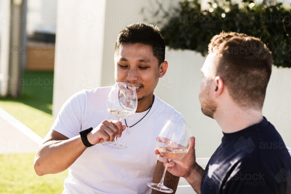 two gay men enjoying a glass of wine in the sunshine - Australian Stock Image