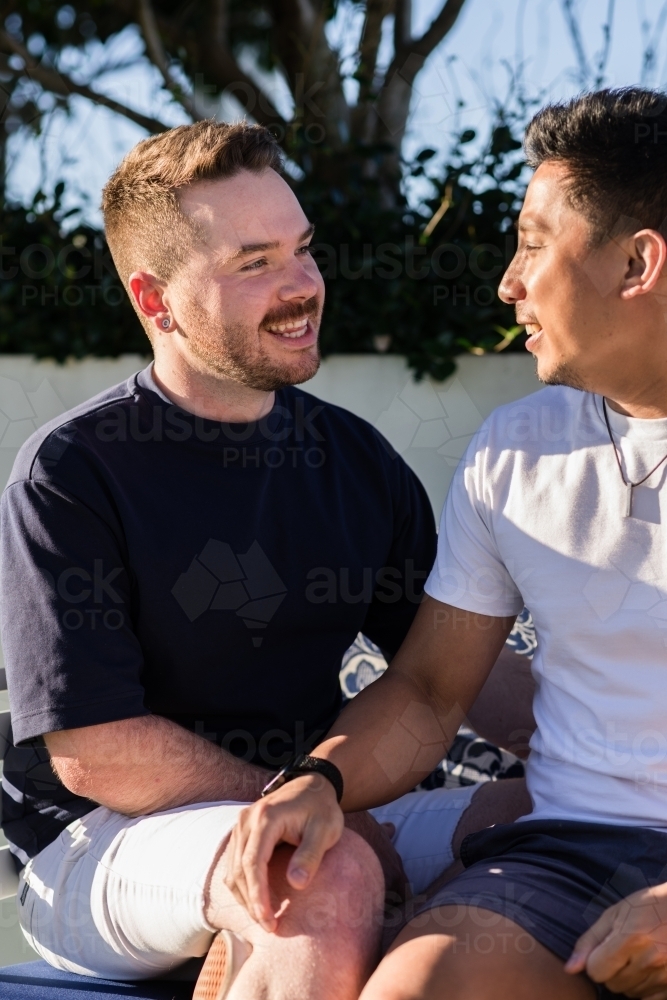 two gay men sitting outdoors in the sunshine - Australian Stock Image