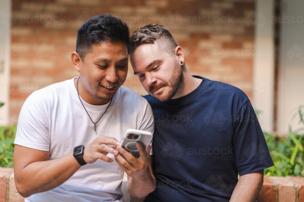 two gay men using a phone - Australian Stock Image