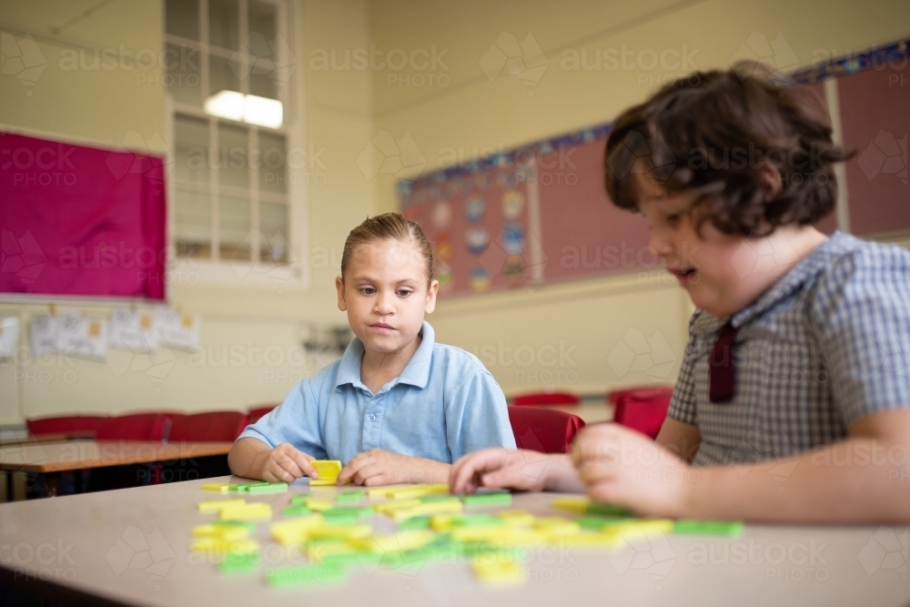 Two girl school students collaborating with coloured word tiles - Australian Stock Image