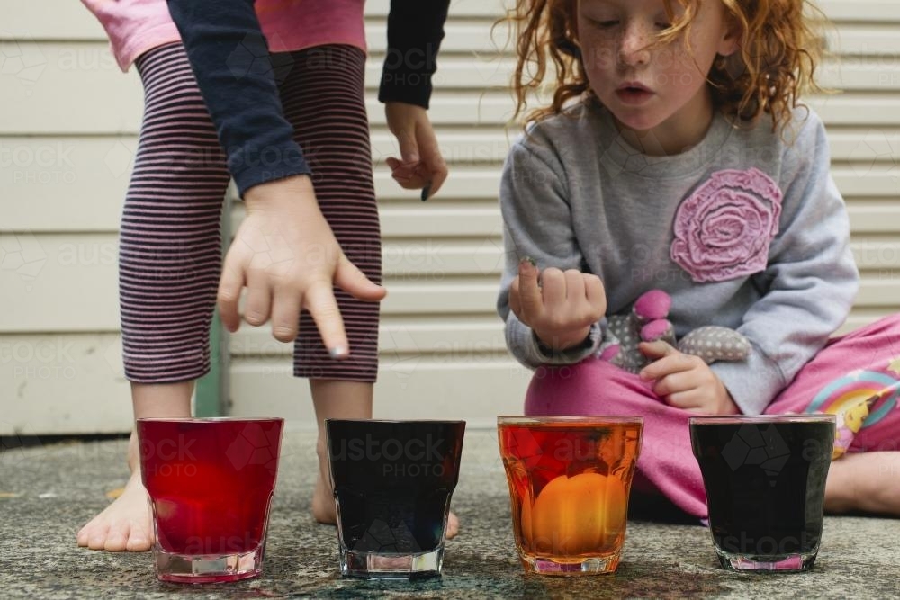 Two girls colouring eggs with food dye - Australian Stock Image