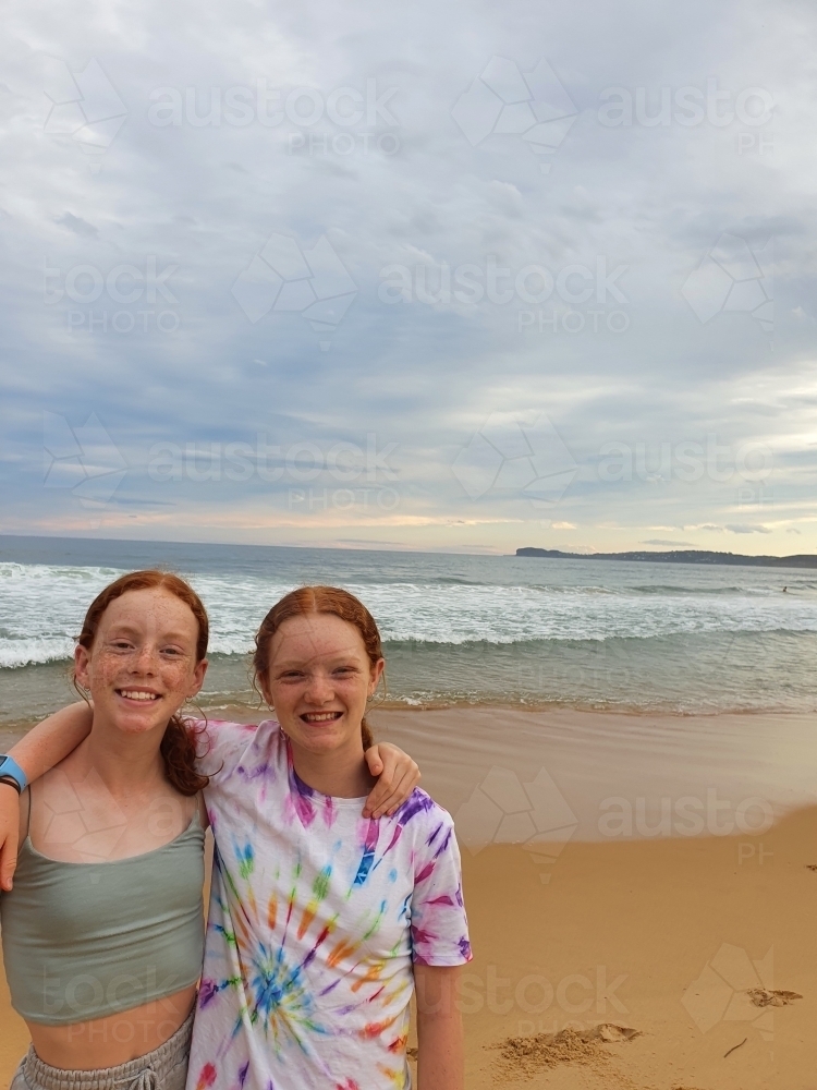 Two girls happy at the beach at sunset - Australian Stock Image